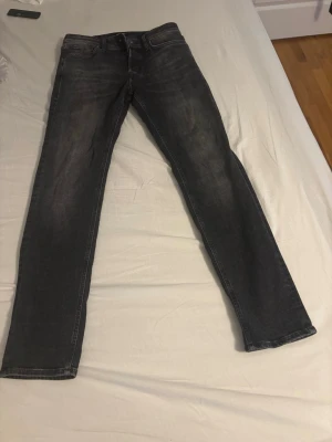 Mörkgrå raka jeans - Säljer ett par mörkgrå jeans med raka ben och klassisk femficksdesign. Jeansen har en diskret tvättad look och normal passform. Perfekta till en avslappnad stil och funkar året runt.