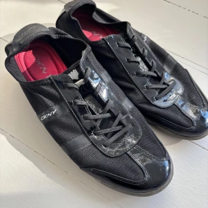 Sneakers DKNY strlk 40 - Svarta sneakers med snygga lackdetaljer DKNY strlk 40. Bra skick.