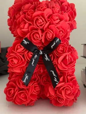 Nallebjörn av röda rosor med rosett - Unik nallebjörn formad av röda konstgjorda rosor, dekorerad med en svart rosett med texten 'Just for you'. Perfekt som present eller dekoration till någon speciell. Tillverkad av mjukt skumgummimaterial för en exklusiv känsla.