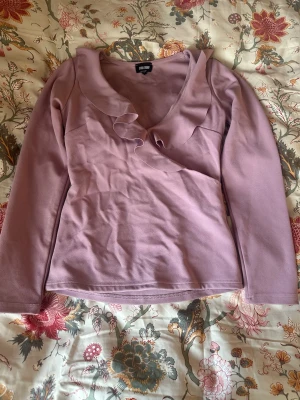 Ljuslila topp med volang från Bubbleroom - Supersöt ljuslila topp från Bubbleroom med v-ringning volang. Jätte fint skick. Strl S. Säljer för att jag inte tycker den färgen passar just mig