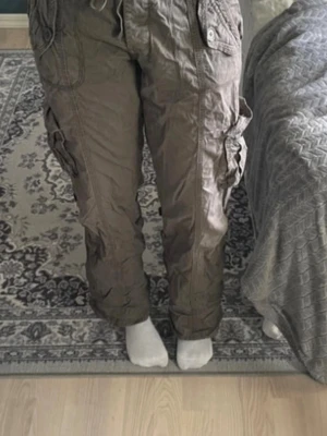 Bruna cargobyxor med fickor - Säljer ett par bruna cargobyxor med flera stora fickor på sidorna och bak. Går även att knyta upp till shorts. Byxorna har en avslappnad passform och är tillverkade i ett slitstarkt bomullsmaterial. Perfekta för dig som gillar streetwear och praktiska detaljer.