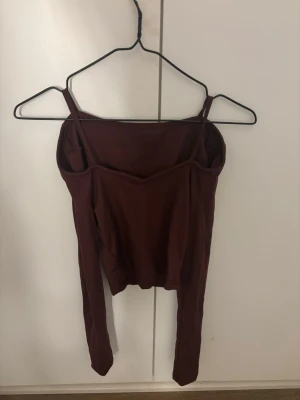 Vinröd långärmad topp - Säljer en vinröd långärmad topp med smala axelband och figurnära passform. Toppen har en enkel och stilren design som passar perfekt till jeans eller kjol. Materialet känns mjukt och stretchigt, vilket gör den bekväm att bära.
