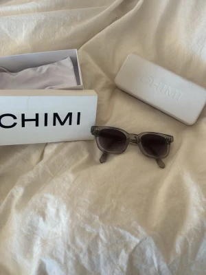 Grå CHIMI solglasögon i acetat - Snygga solglasögon från CHIMI med grå, transparent båge i acetat och mörka glas. Klassisk, fyrkantig form som ger en modern look. Kommer med originalfodral och box. Helt nya använda Max 1-2 gånger!