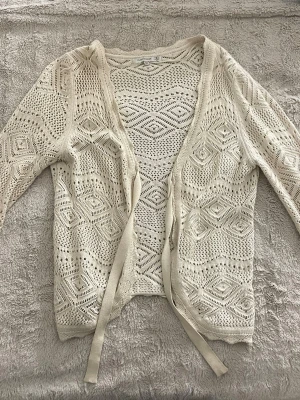 Söt  virkad kofta med knytband - Söt  virkad kofta med långa ärmar och dekorativa diamantmönster. 