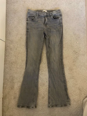 gråa utsvängda jeans - gråa utsvängda jeans från gina!! ganska bra skick små slitningar längst ner men inget illa!