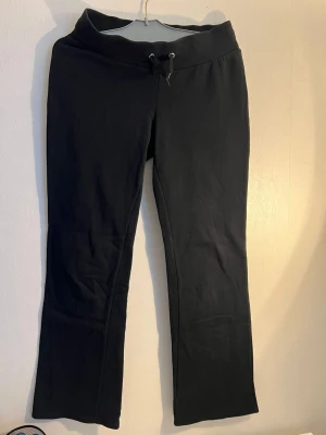 Svarta bootcut mjukisbyxor - Svarta mjukisbyxor med bootcut passform och bred resår i midjan samt dragsko. Tillverkade i mjukt och stretchigt material som ger en skön känsla. Perfekta för en avslappnad stil och passar till hoodie eller crop top.
