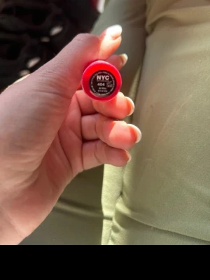 NYC Expert Last Läppstift 404 Air Kiss - Säljer ett NYC Expert Last läppstift i färgen 404 Air Kiss. Läppstiftet har en intensiv rosa nyans och kommer i en klassisk rund plastförpackning med genomskinligt lock. Perfekt för dig som vill ha en färgstark look.