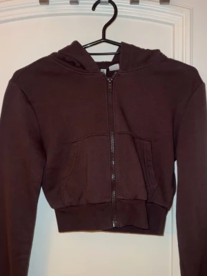 Brun croppad hoodie med dragkedja - Säljer en brun croppad hoodie med dragkedja framtill. Hoodien har långa ärmar och en huva. Materialet känns mjukt och bekvämt. Pris går att diskutera. 💞 