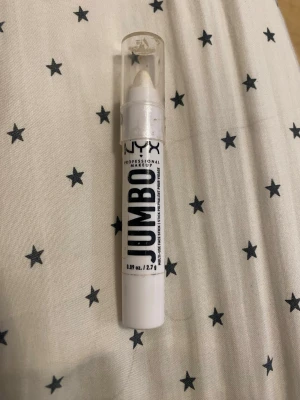 NYX Jumbo ögonskuggspenna vit - NYX Professional Makeup Jumbo ögonskuggspenna i färgen vit med skimrande finish. Pennan har en krämig konsistens och är enkel att applicera direkt på ögonlocket. Perfekt för att skapa ljusa och intensiva ögonlooks. Praktisk pennform med genomskinligt lock.