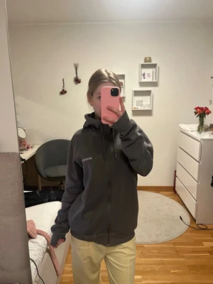 Grå hoodie med dragkedja från McKenzie - Säljer en grå hoodie från McKenzie med dragkedja och huva. Materialet är mjukt och bekvämt, perfekt för chill dagar. Långa ärmar och ribbade muddar gör den extra skön.