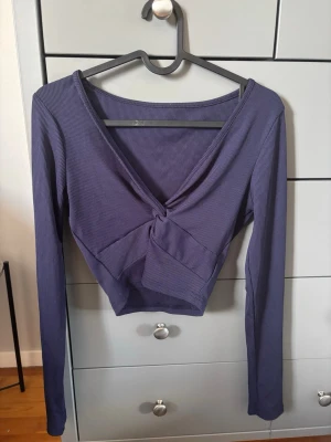 Marinblå v-ringad topp - Trendig marinblå croppad topp med lång ärm och snygg v-ringning framtill. Toppen har ribbad struktur och djup v-ringning som ger en modern look.