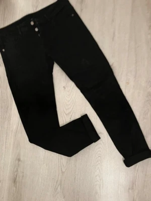 Svarta skinny jeans  nya - Snygga svarta skinny jeans med  klassisk femficksdesign. Jeansen har hög midja och stängs med två knappar och dragkedja. Perfekta till en avslappnad streetstyle-look.