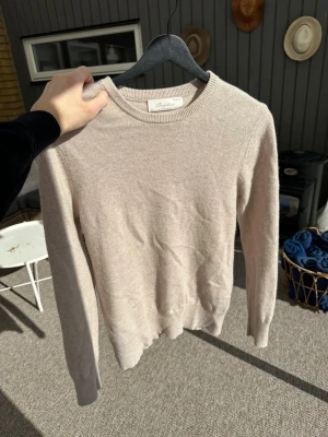 Beige stickad tröja sayless - Mysig beige stickad tröja från sayless i klassisk modell med rund halsringning och långa ärmar. Tröjan är tillverkad i mjukt material och har ribbade muddar vid ärmslut och nederkant. Perfekt för lager på lager under kyliga dagar.