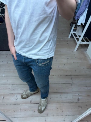 Blåa diesel jeans - Säljer ett par blå jeans från Diesel med klassisk femficksdesign och diskreta detaljer på fickorna. Jeansen har normal midja och är tillverkade i ett mjukt denimtyg med lätt tvättad look. Jeansen är använda 1 max 2 gånger och har inga defekter. Storleken är 30/32. 