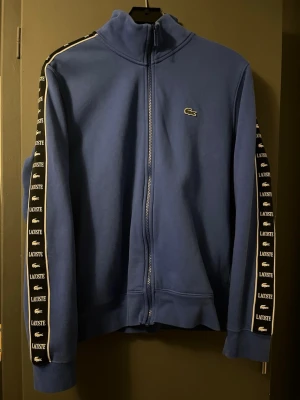 Blå zip hoodie från Lacoste - Snygg blå zip hoodie som knappt är använd. Väldigt bra skick. Väldigt snygg