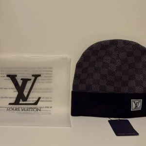 Mössa - Snygg svart och grå mössa med klassiskt rutmönster och vikt kant. framtill på kanten och diskret etikett på insidan. Perfekt accessoar för dig som vill ha en exklusiv och trendig look.