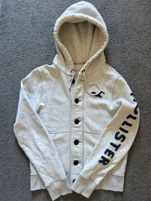Vintage Hollister Cardigan Med Knappar - Säljer denna otroliga sällsynta och feta Hollister cardigan med knappar | Mycket bra skick förutom  smuts på slutet av båda ärmen se sista bilder | Längd ≈ 66cm, Bredd armhåla - armhåla 55 cm | Modell 175, 68 kg