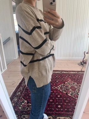 Stickad tröja från BikBok - Beige med svarta ränder och en slit på båda sidor längst ner.