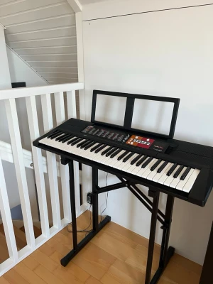 Svart Yamaha keyboard med notställ - Elektroniskt keyboard från Yamaha i svart med vita och svarta tangenter, digital display och flera kontrollknappar. Medföljer ett stabilt notställ och stativ. Perfekt för att spela och öva hemma, ansluts med strömkabel.