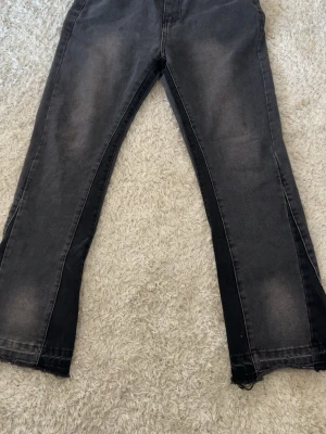 Gallery dept flared S - Säljer ett par svarta jeans med raka ben och snyggt slitna detaljer. Jeansen har en tvättad look med ljusare partier och råa, fransiga benslut för en trendig vibe. Perfekta för dig som gillar en avslappnad och cool stil.