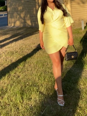 Gul omlottklänning med v-ringning - Kort ljusgul klänning med omlott-design och v-ringad hals. Klänning köpt från ASOS