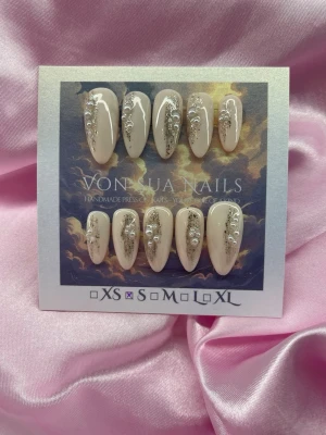 Luxe (S);Medium Almond - Handgjorda press-on naglar i beige nyans med guldrglitter och vita pärldekorationer. Naglarna har en medium lång, mandelformad design. Perfekt för dig som vill ha en elegant och unik look.S: 15 mm, 11,5 mm, 12 mm, 11 mm, 9 mm 
