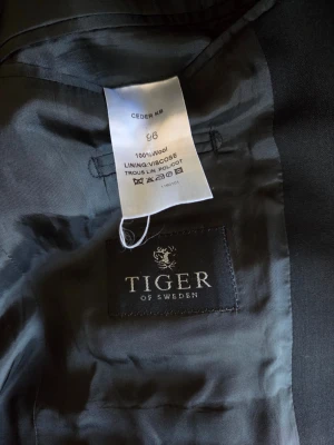 Tiger of Sweden Kostym – Modell Ceder KB – 100% Ull - Säljer nu en riktigt snygg kostym i modellen Ceder KB. En modern klassiker med perfekt passform för dig som vill ha en slimmad look men behöver lite extra längd! ​Storlek: 96 (Slim fit, perfekt för ca 180–195 cm). ​Material: Premium 100% ull – andas och sitter snyggt. ​Detaljer: Enkelknäppt kavaj med dubbla sprund och matchande kostymbyxor med pressveck. 