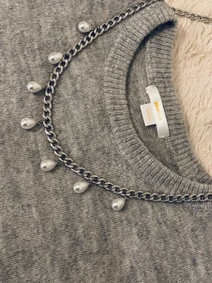Kedjehalsband med droppformade pärlor - Snyggt halsband med en silverfärgad kedja och droppformade vita pärlor som hänger längs hela kedjan. Perfekt accessoar för att lyfta din outfit med en trendig och stilren touch.