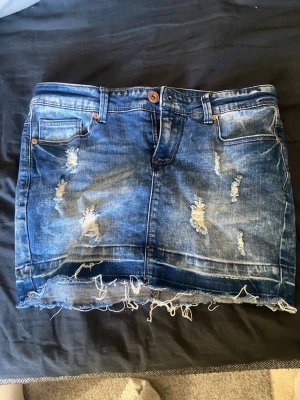 Blå jeanskjol med slitningar från ONLY - Cool blå jeanskjol från ONLY med slitna detaljer och fransig nederkant. Säljer då den inte används, skriv om du har frågor💕 storlek xs/s passar båda