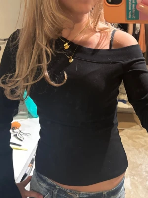 Svart offshoulder topp - Snygg svart offshoulder topp med lång ärm och figurnära passform. Perfekt för dig som vill ha en stilren och trendig look. Toppens enkla design gör den lätt att matcha med olika outfits.