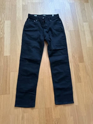 Svarta jeans från Jack & Jones - Säljer ett par svarta jeans från Jack & Jones i klassisk rak modell. Jeansen har fem fickor, bälteshällor och stängs med knapp och dragkedja. Perfekta för dig som gillar en enkel och stilren look.