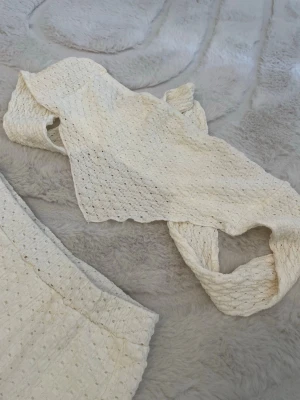 Vitt spetsset med topp och kjol - Säljer ett vitt tvådelat set med en kort topp och matchande kjol i broderad spets. Oanvänd storlek S, kjolen har ett under tyg