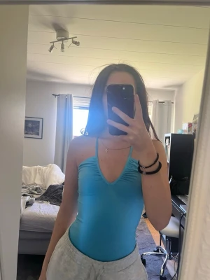 Turkos body med halterneck - turkos body med halterneck och djup urringning framtill. Enkel och stilren design med stretchigt material.