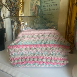 Pastellfärgad virkad kuvertväska - Superfin kuvertväska i virkade pastellfärger med inslag av rosa, mintgrönt och beige. Väskan har en mjuk, rektangulär form och ett unikt mönster med bubbliga detaljer. Perfekt accessoar för att lyfta din outfit med en söt och färgglad touch. Skriv till mig om du har prisförslag eller frågor💕