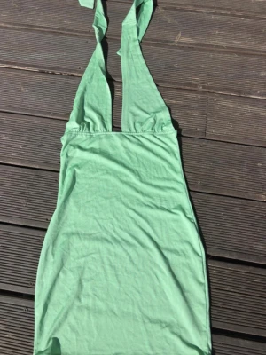 Mintgrön klänning från NLY ONE - Snygg mintgrön kortklänning från NLY ONE med knytbara axelband och djup v-ringning. Klänningen är ärmlös och har en enkel, figurnära passform i mjuk bomull. Perfekt för varma dagar och somriga vibes.