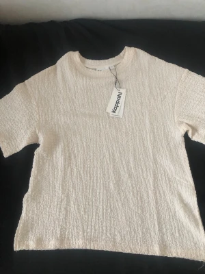 Crémevit topp från Kappahl i storlek S - Jätte fin topp i färgen crémevit och storlek S. Tröjan är från Kappahl och är helt oanvänd. Tröjan har även slitsor på sidorna. Nypriset på tröjan är 249kr som ni kan se på prislappet.