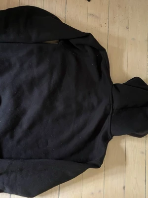 Svart hoodie från Polo Ralph Lauren - Klassisk svart hoodie från Polo Ralph Lauren med den ikoniska broderade loggan på bröstet. Hoodien har huva och är tillverkad i mjukt material som känns skönt mot huden. Perfekt för en avslappnad och stilren look.