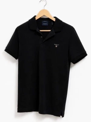 Svart pikétröja från GANT (S) - Klassisk svart pikétröja från GANT med korta ärmar och liten broderad logga på bröstet. Tröjan har krage och knappar framtill. Sparsamt använd. Gjord i bomull för en skön känsla. Galge ingår ej. Nytvättad men ej strykt. Nypris 899 kr.
