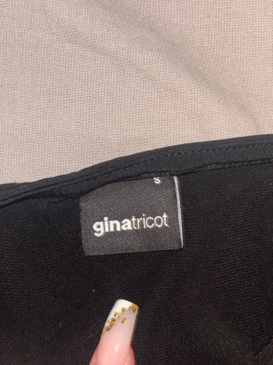 Svart croppad topp Gina Tricot - Säljer en svart croppad topp från Gina Tricot med lång ärm och unik cut out-detalj framtill. Toppen har en tight passform och är perfekt för dig som vill ha en trendig och edgy look. Materialet känns mjukt och stretchigt.
