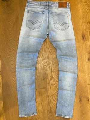 Ljusblå slim jeans från Replay - Säljer ett par ljusblå slim jeans från Replay med slitningar och tvättad look. Materialet är denim i bomull med stretch för extra komfort.