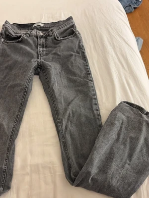 Gråa flare jeans - Säljer ett par gråa jeans som är flare/bootcut jeans och har en klassisk femficksdesign. Jeansen har normal midja och är tillverkade i ett mjukt denimtyg som ger en avslappnad look. Perfekta till en streetwear-outfit eller för en chill vardagsstil.