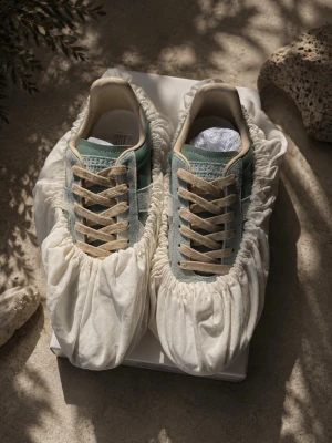 Ljus blå maison margiela gats - Snygga sneakers i färgen ljusblå med beige snören och detaljer. Ovandelen är i mocka och slätt material, och sulan är i gummi. Klassisk låg modell med stilren design som passar till många outfits. Första bilden är ai så siffrorna ser lite konstiga ut