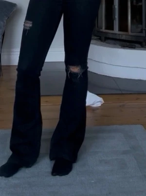 Svarta bootcut jeans med slitningar - Säljer ett par svarta bootcut jeans som är sååå snygga, lite högmidjade men ändå så fina. Skriv för fler frågor