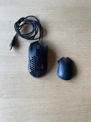Svart gamingmus med utbytbara skal - Säljer en svart gamingmus med rgb lysen, USB-kabel och två utbytbara skal, ett med hexagonmönster och ett slätt. Musen har en ergonomisk form och är tillverkad i plast. Perfekt för dig som vill ha en lätt och anpassningsbar mus till datorn.
