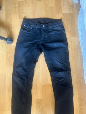 Svarta slim fit jeans - Säljer ett par feta nudie jeans i modellen ”Grim Tim”. 30/34. ny pris 1600kr men mitt pris är 200 då de har ett hål i vänstra fickan. Dock nudie har gratis repair vid deras butiker så se det som en investering!