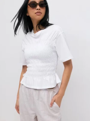 Vit smockad topp med kort ärm - Säljer en vit topp med smockad midja och korta ärmar. Toppen har en lätt volang nedtill och är i mjukt bomullsmaterial. Perfekt till både jeans och kjol för en fräsch look. Aldrig använd. Nypris 280 kr, mitt pris 150 kr. 