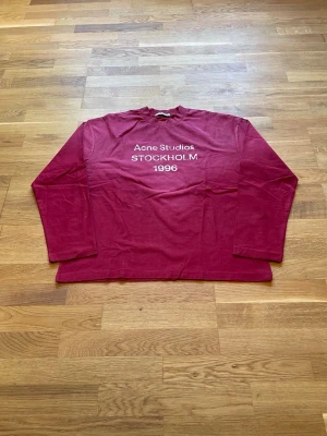 Acne Studios Longsleeve  - Säljer en as fet Acne Studios Longsleeve med det klassiska "Acne Studios STOCKHOLM 1996" trycket på bröstet. Tröjans röda färg samt att den är i Longsleeve-varianten gör att den sticker ut i mangden. Storlek: Small men passar mer som medium. Mått- Längd: 66.5 cm. Axel till axel: 56 cm. Armhåla till armhåla: 57.5 cm. Helt ny! Skickas inom 24 timmar. Skriv vid funderingar!