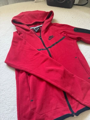 Röd Nike hoodie med dragkedja - Snygg röd hoodie från Nike med hel dragkedja och svarta detaljer. Passar XS och S med , män&kvinnor