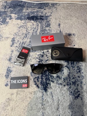 Svarta Ray-Ban Wayfarer solglasögon - Klassiska svarta Ray-Ban Wayfarer solglasögon med blank finish och mörka glas. Säljs med originalfodral, putsduk och box. Perfekt accessoar för dig som vill ha en tidlös och ikonisk look. Kan gå ner i pris vid snabb affär