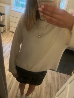 Svart paljettkjol från Lindex - Säljer en svart kortkjol från Lindex täckt med glittriga paljetter. Kjolen har en tajt passform och är perfekt för dig som vill sticka ut lite extra. Materialet känns mjukt och följsamt mot kroppen.